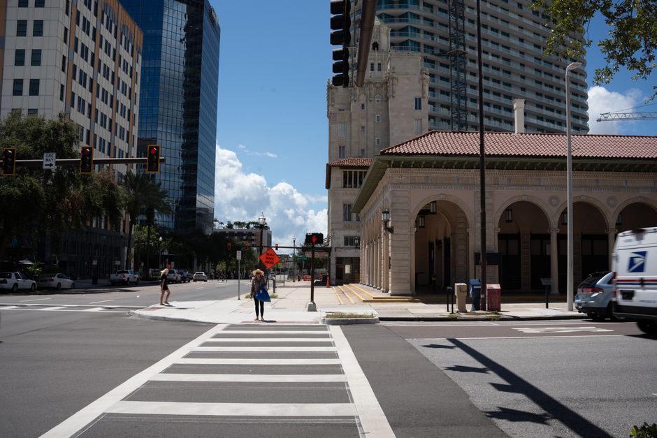 Street scene with historic building, modern skyscrapers, and pedestrians crossing at an intersection.