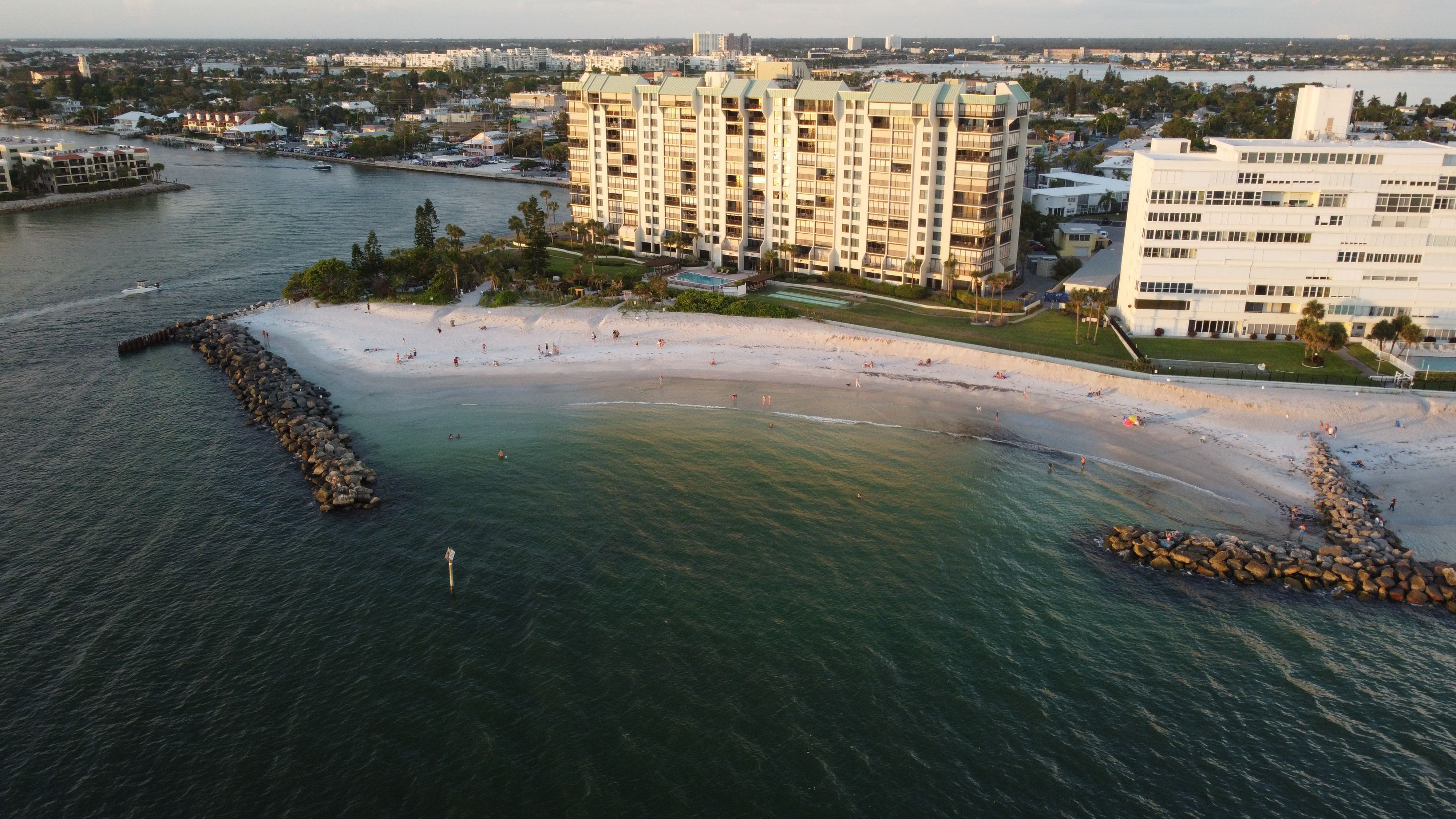 Aerial shot of a serene beach with high-rise apartments and calm waters during sunset.