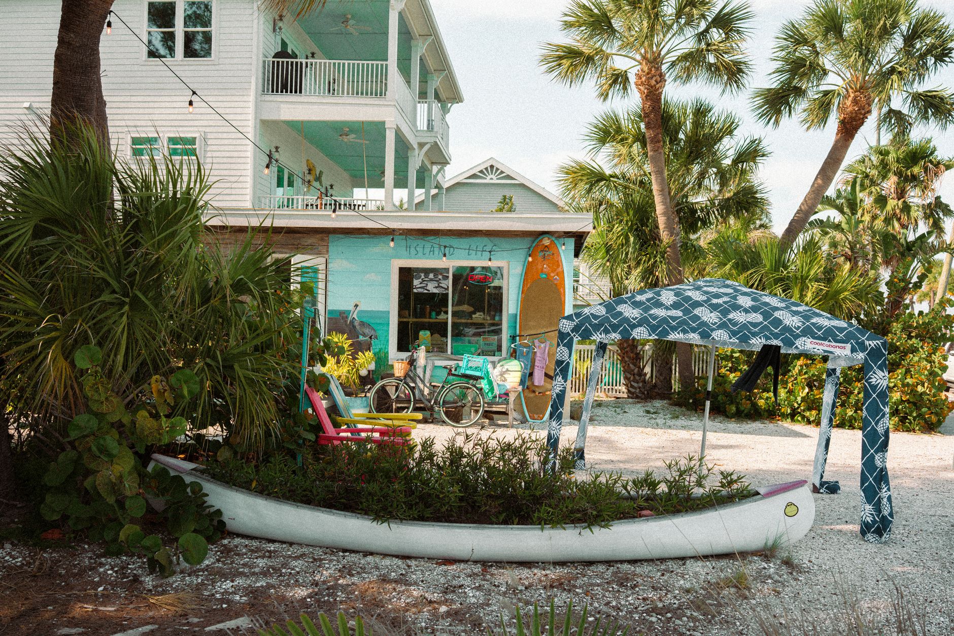 A sunny beachfront shop with a surfboard and bicycle outside.