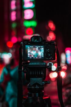 Capture the vibrant night street scene with stunning bokeh using a DSLR camera.