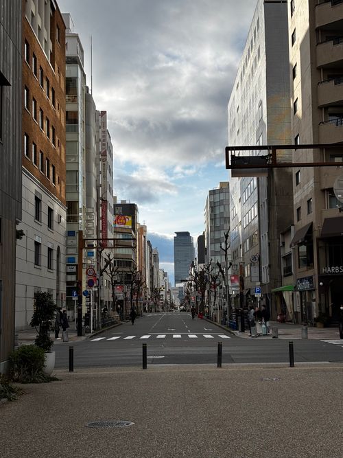 Free A bustling street in Nagoya, Japan showcasing modern architecture under a partly cloudy sky. Stock Photo