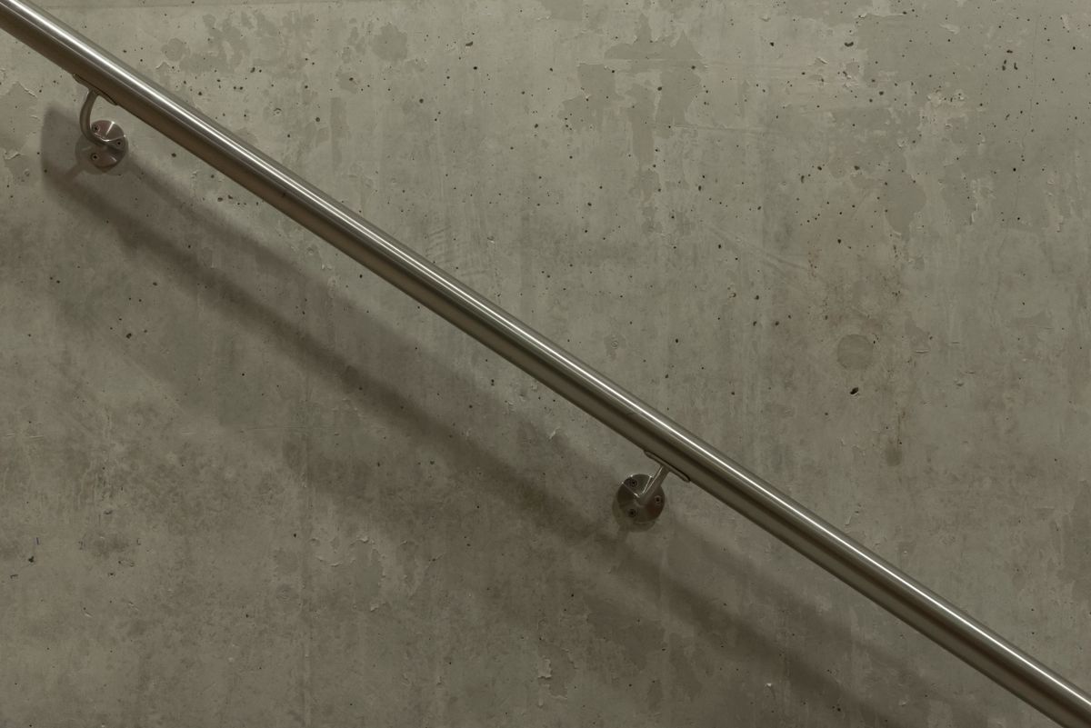 A stainless steel handrail mounted on a concrete wall