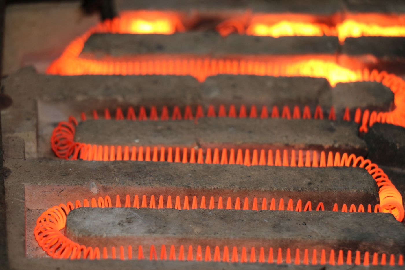 Glowing electric heating element coil radiating heat inside a furnace
