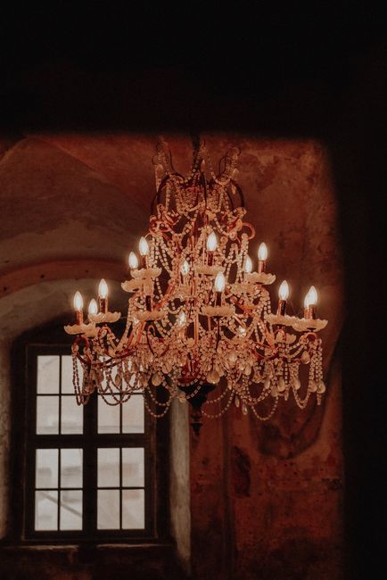 A vintage chandelier with crystal adornments glows warmly in a dimly lit room, evoking classic elegance.
