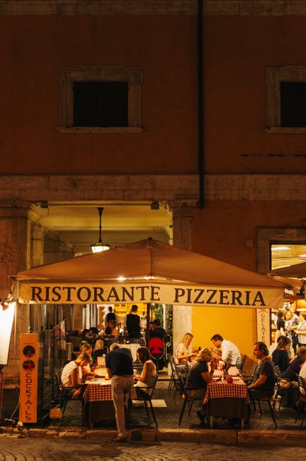 Evening diners enjoying a meal at a traditional Italian pizzeria in Rome, Italy.