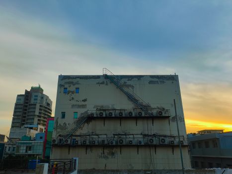 Cityscape featuring a tall building with external staircase at sunset in Sahibzada Ajit Singh Nagar, India.