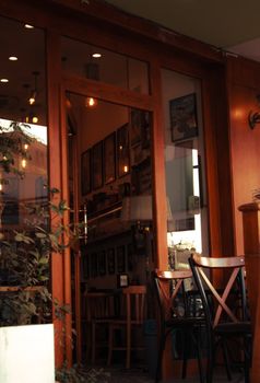 Charming cafe entrance with wooden door, inviting interior, and warm atmospheric lighting.
