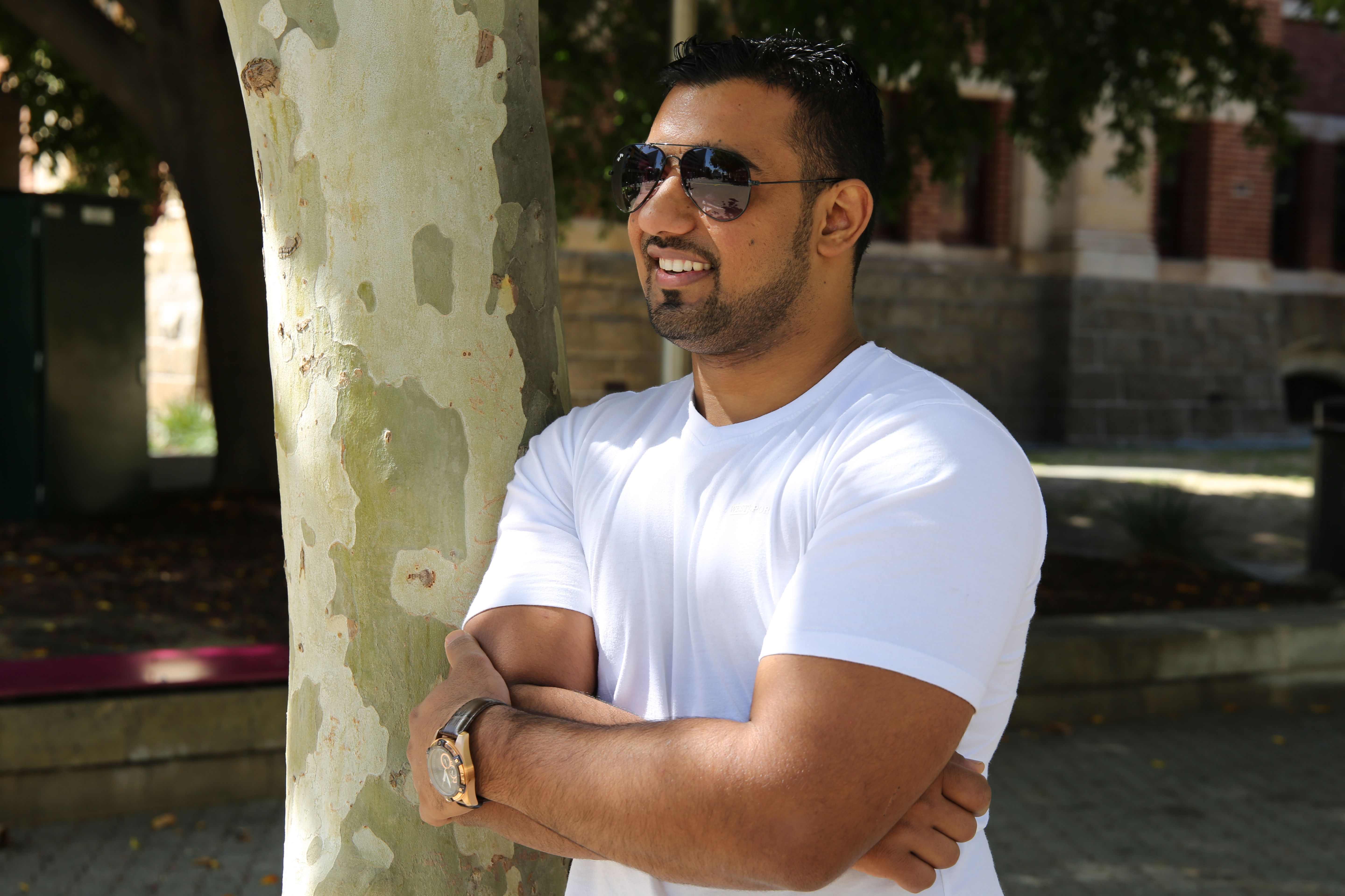 Ahmad Al Khatib leads an outdoor fitness session for a diverse group of participants on a sunny urban plaza.