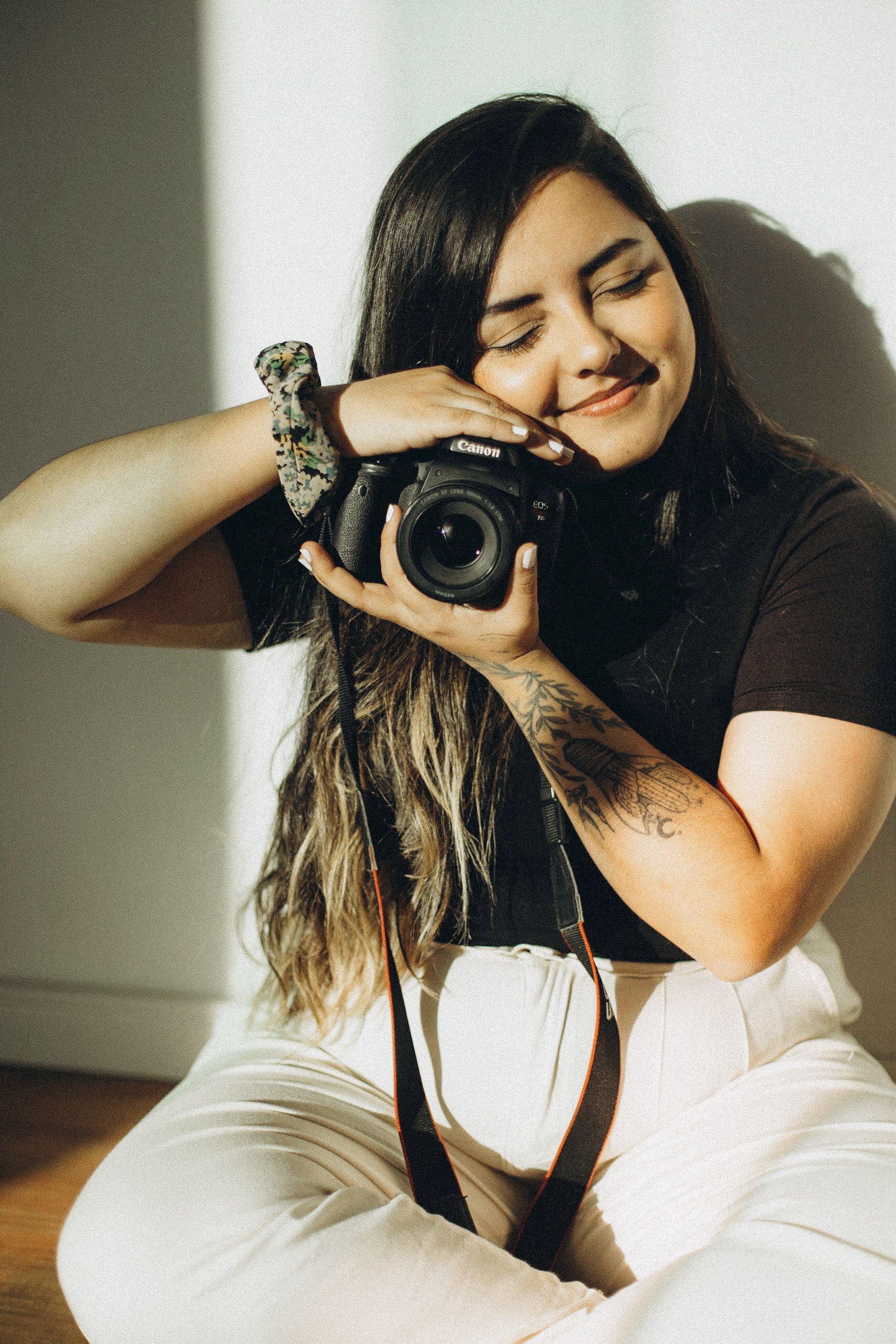 Young female photographer enjoying a peaceful moment with her camera indoors.
