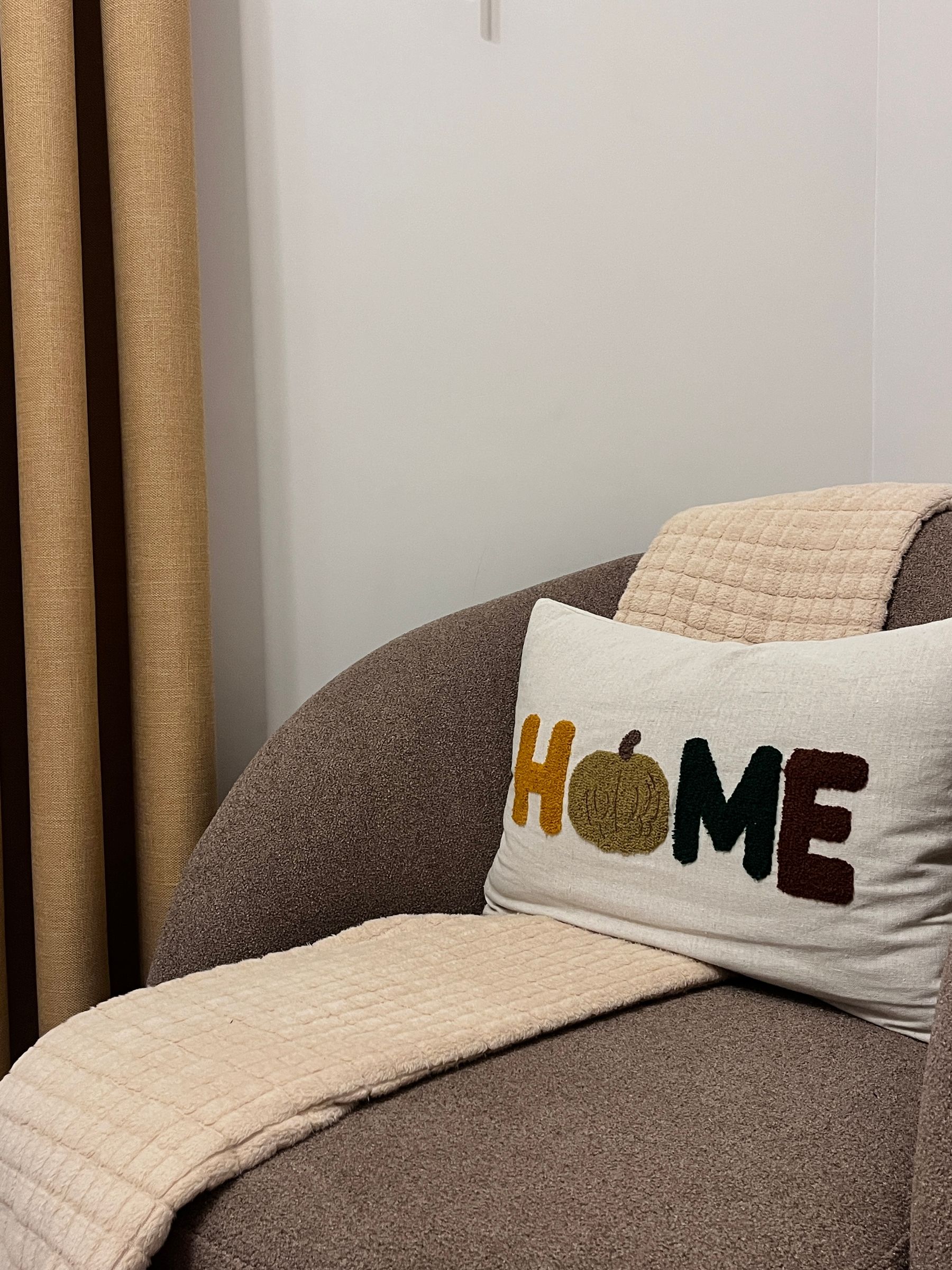 Modern neutral living room with warm autumn pillow and soft seasonal styling