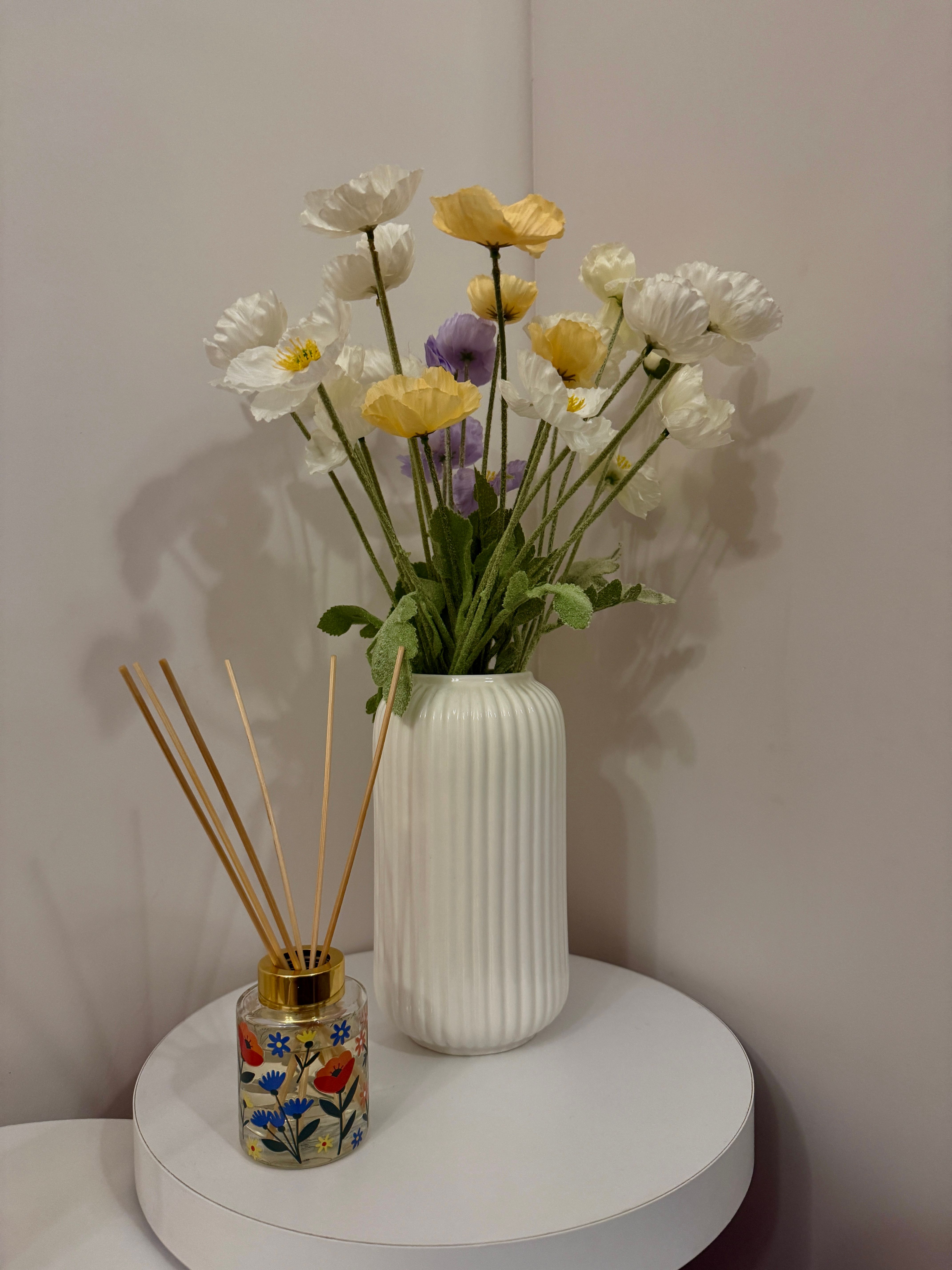Floral arrangement beside a reed diffuser on a sideboard, styled as a decorative object