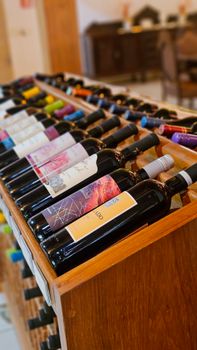 A diverse collection of wine bottles neatly arranged on a wooden rack, showcasing vibrant labels.