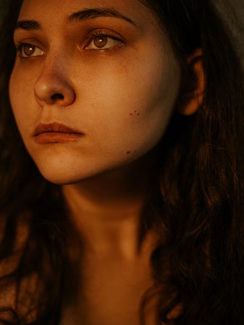 Free Close-up of a young woman's face with soft lighting highlights her thoughtful expression. Stock Photo
