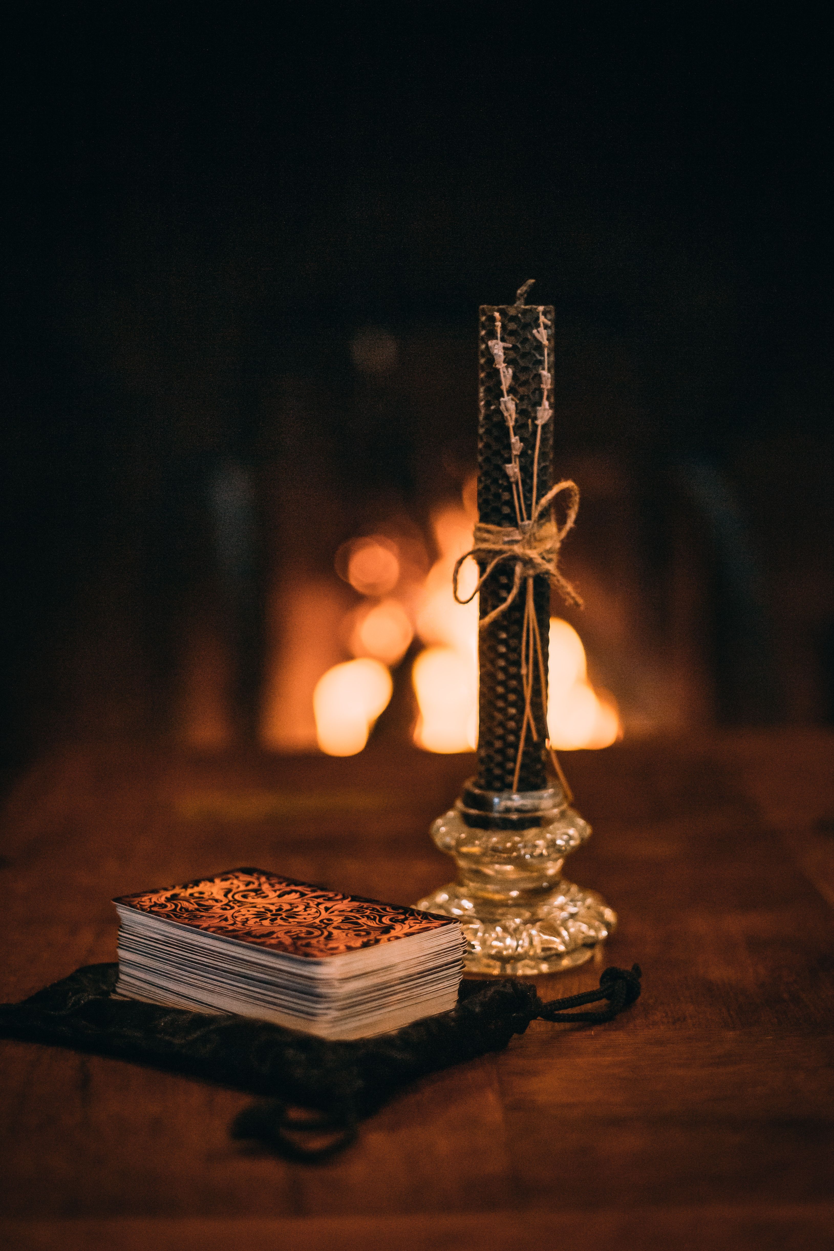 A stack of tarot cards beside a candle creates a mystical and cozy atmosphere.