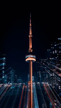 Dramatic night shot of the CN Tower in Toronto with vibrant light trails creating an artistic effect.