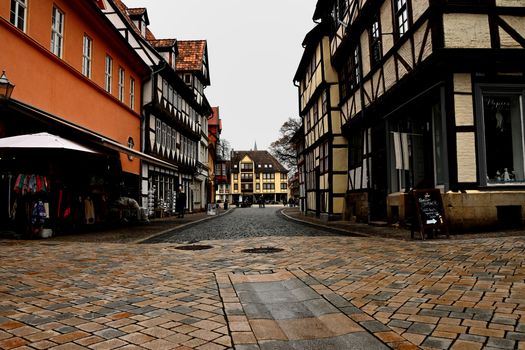 Historic European street with half-timbered houses under an overcast sky, capturing old-world charm.
