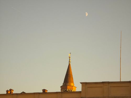 Free Gothic-style tower in Milano with the moon in view under a clear sky at twilight. Stock Photo