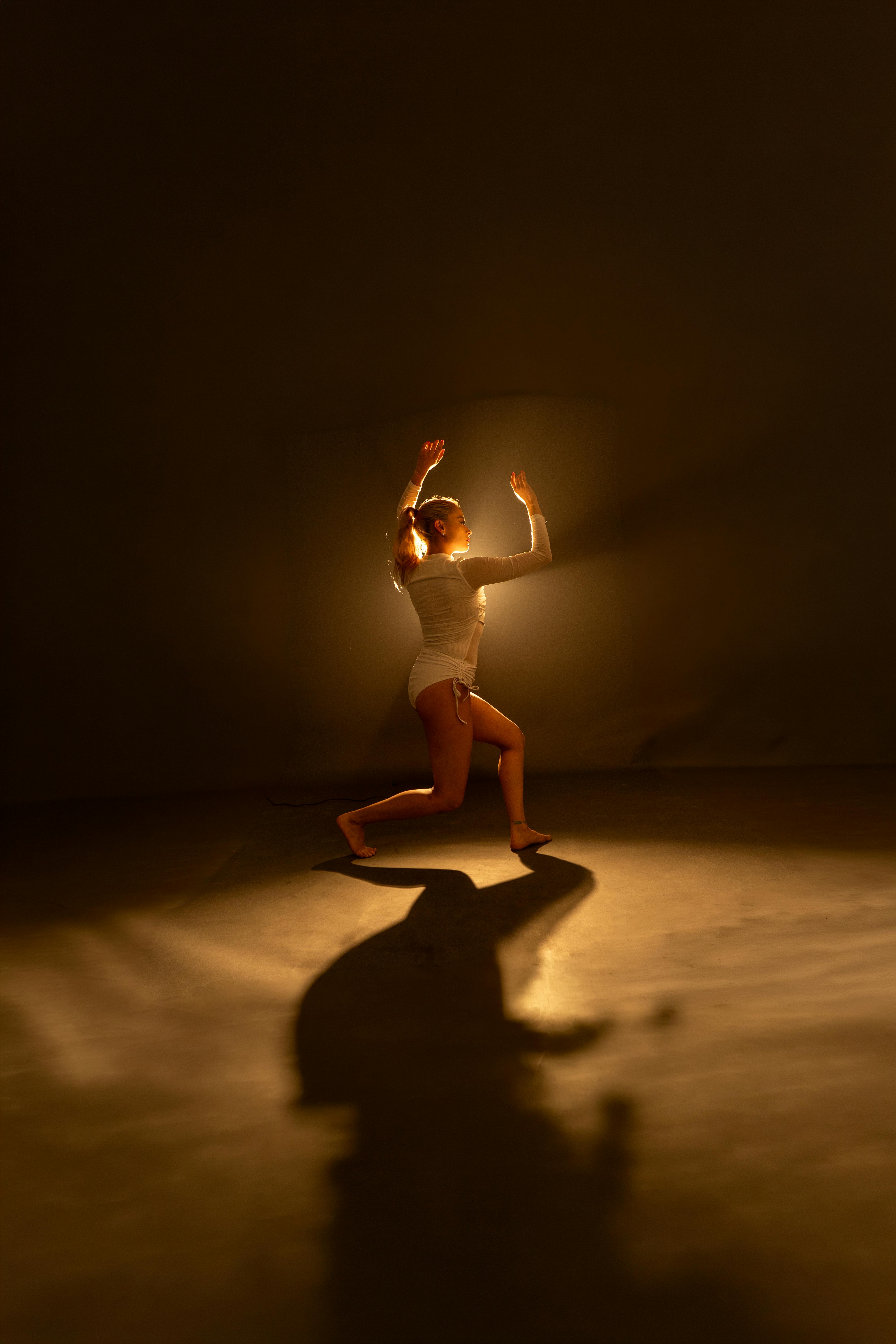 A contemporary dancer captured in motion with dramatic studio lighting creating striking shadows.
