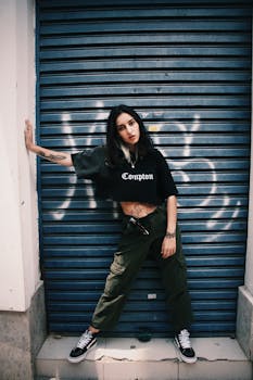 城市时装模特身着休闲街头服装，在涂鸦背景的户外摆着姿势