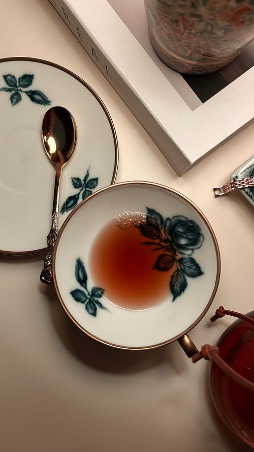 Free A beautifully decorated teacup with tea and saucer on a cozy tabletop scene. Stock Photo