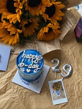 Colorful birthday setup with a blue cake, sunflowers, and Polaroid.
