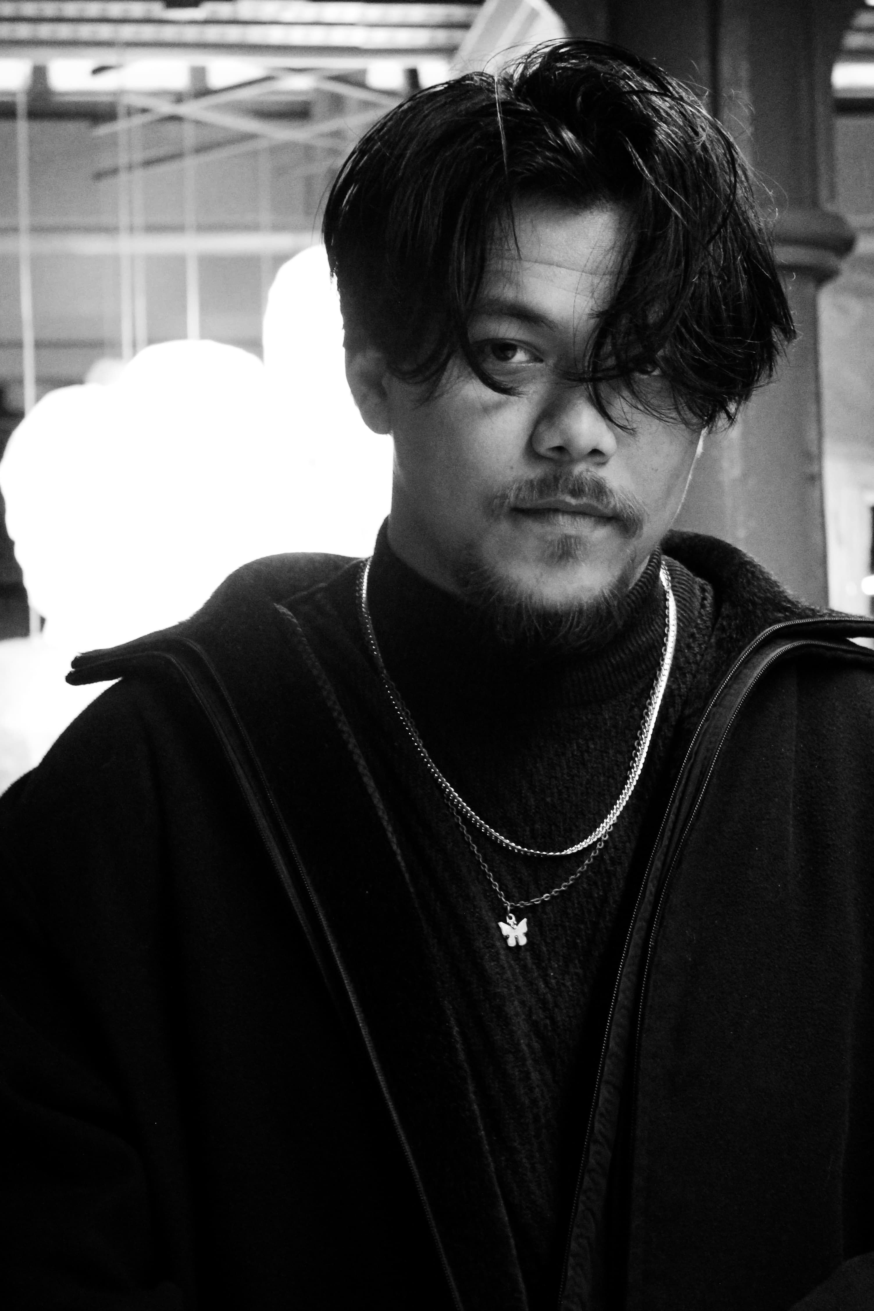 Moody black and white portrait of a fashionable young man indoors.