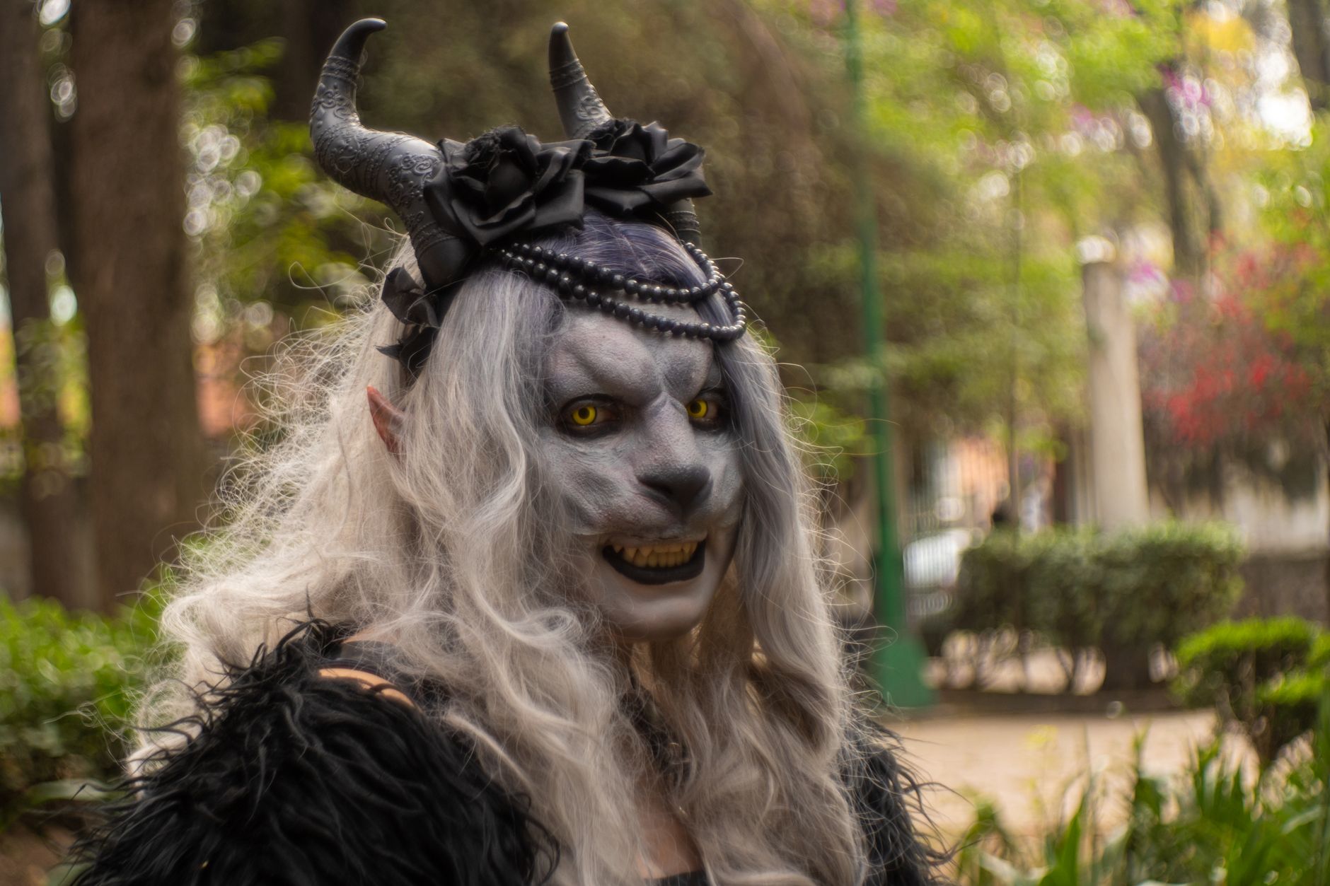 A captivating character with a horned costume stands in a vibrant park in Mexico City, Mexico.