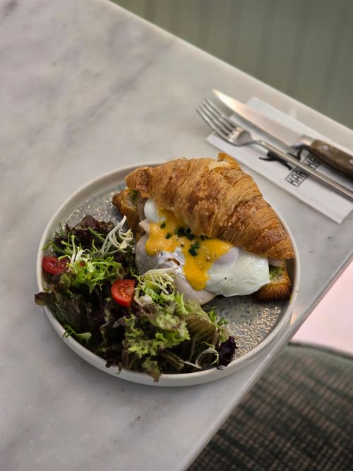 Free Delicious croissant sandwich with creamy egg and fresh salad served on marble surface. Stock Photo