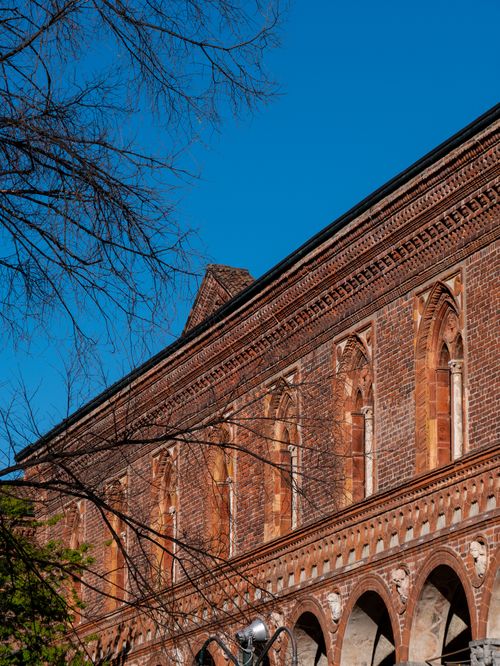 Free A historic brick building with ornate windows against a clear blue sky, showcasing architectural beauty. Stock Photo