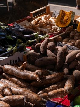 Vibrant display of fresh produce at an outdoor market with various vegetables and tubers.