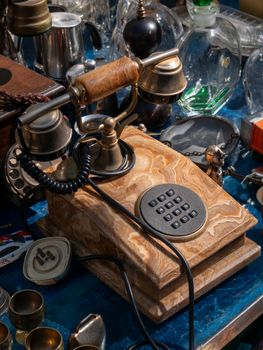 Close-up of a classic rotary phone on a table surrounded by vintage items.