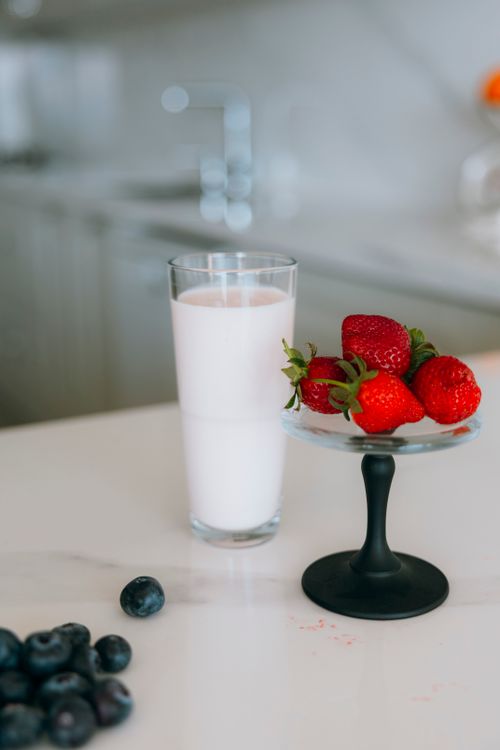 Free A glass of berry smoothie next to fresh strawberries and blueberries in a modern kitchen. Stock Photo