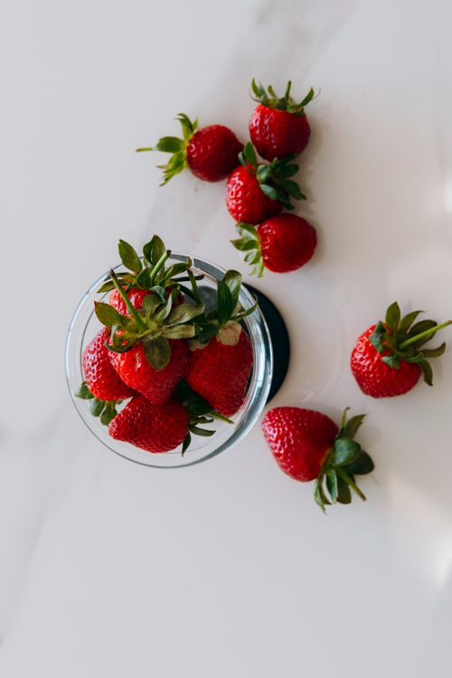 Free Top view of fresh strawberries in a glass bowl on a marble surface, perfect for food-related content. Stock Photo