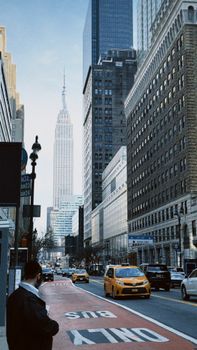 View of busy New York City street with the iconic Empire State Building and yellow taxis.