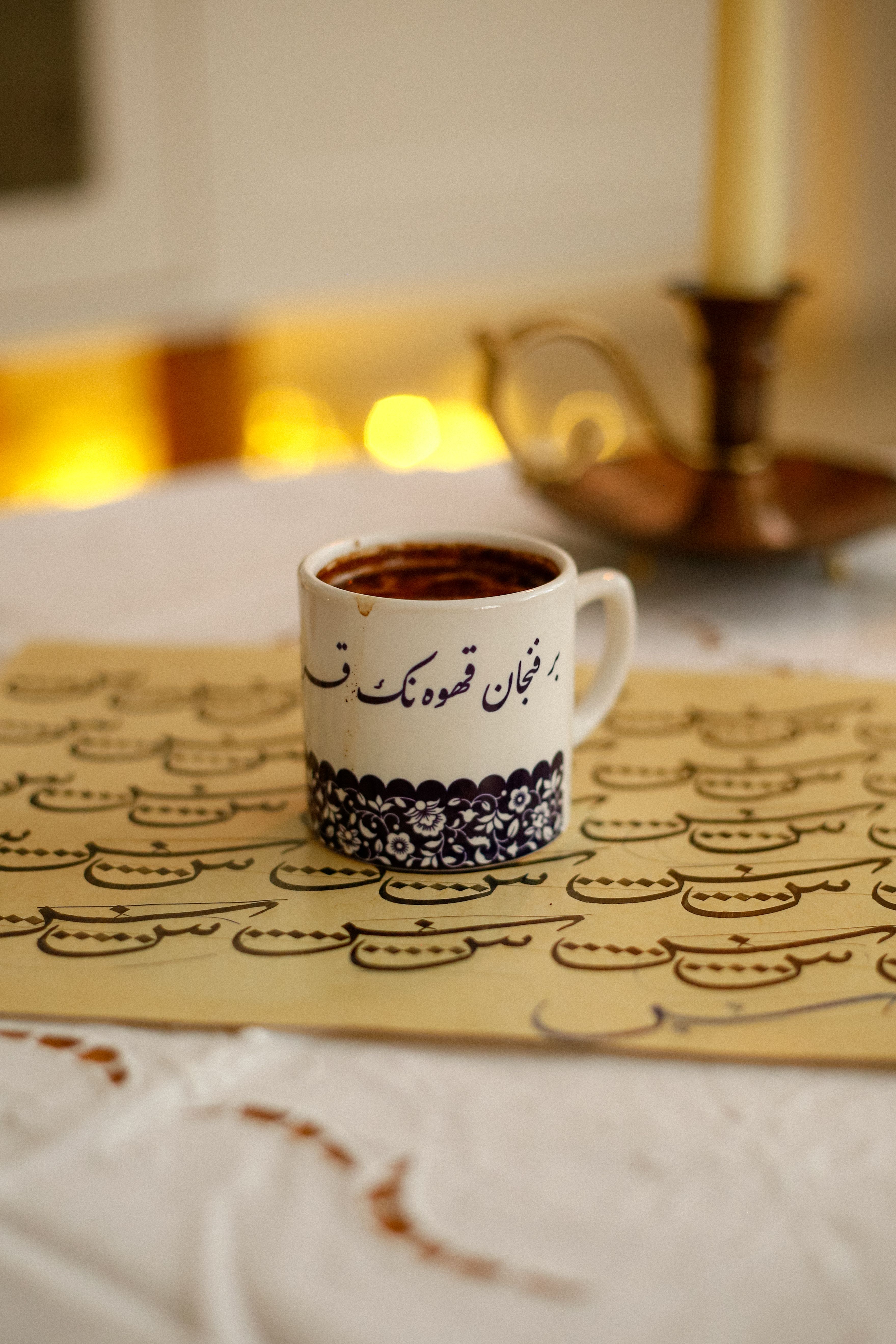 Intricate coffee cup on decorative mat with warm lighting for a cozy ambiance.