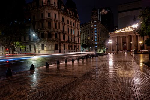 Free Illuminated historic architecture in Buenos Aires during nighttime with street lights reflecting on wet pavement. Stock Photo