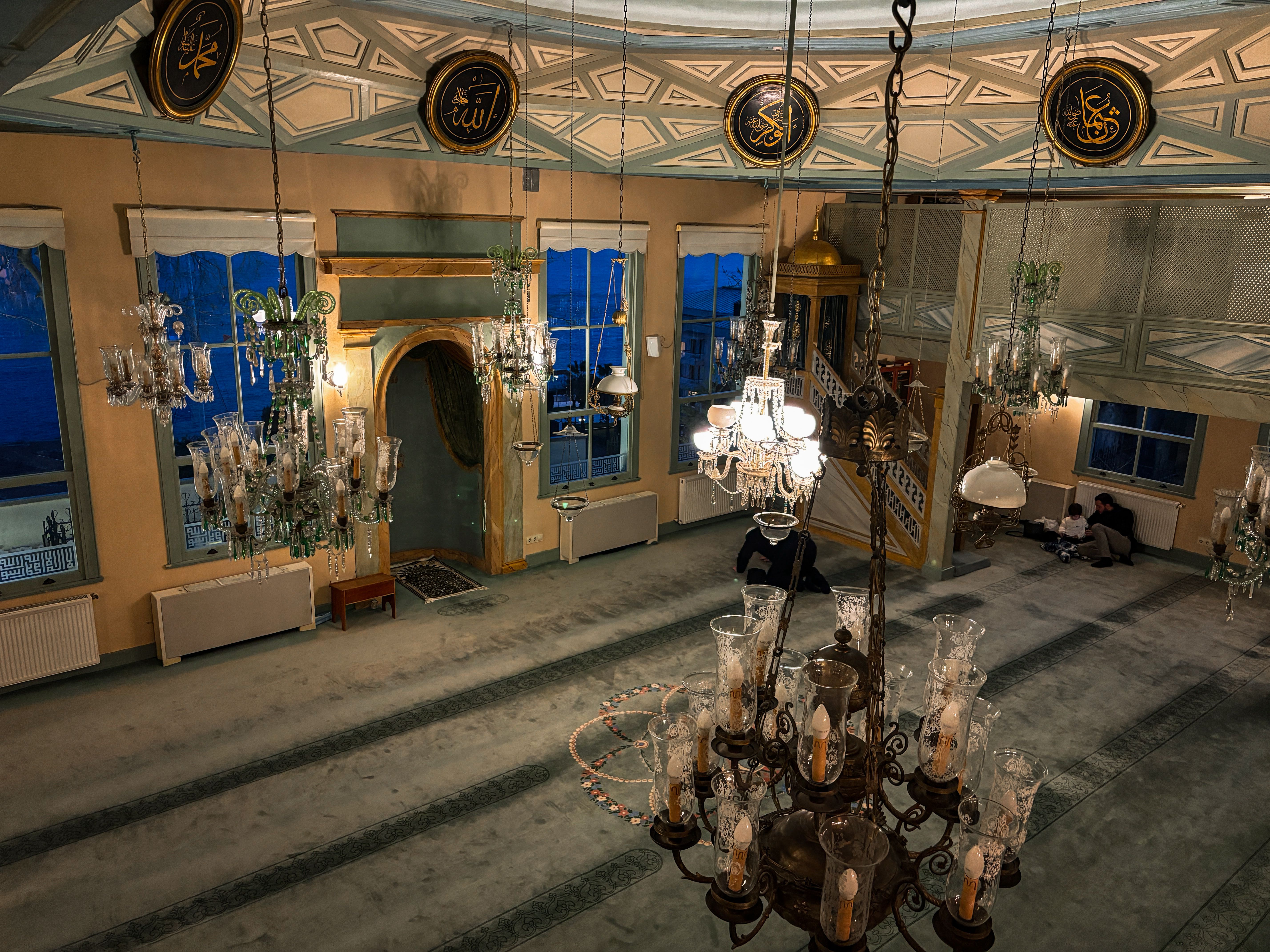Elegant mosque interior with ornate chandeliers, intricate architecture, and rich cultural details.