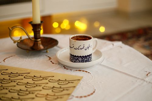 Free A cup of Turkish coffee with intricate designs, surrounded by an ornate candle holder and calligraphy. Stock Photo