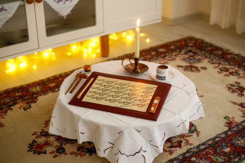 Free A cozy indoor scene with traditional calligraphy, candlelight, and tea on a beautifully set table. Stock Photo
