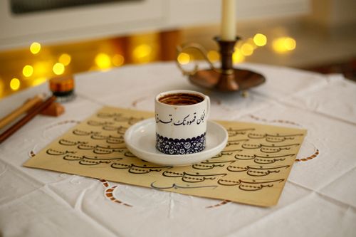 Free A cozy indoor scene featuring Turkish coffee, traditional calligraphy, and warm candlelight. Stock Photo