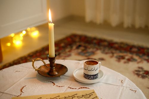 Free Warm indoor scene with a lit candle and coffee cup on a decorative table. Stock Photo