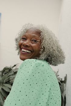 Radiant senior woman smiling outdoors in a vibrant green outfit.