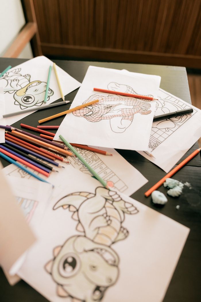 Colourful printed line-art sheets and pencils spread across a desk — photo by Alexander Mass on Pexels
