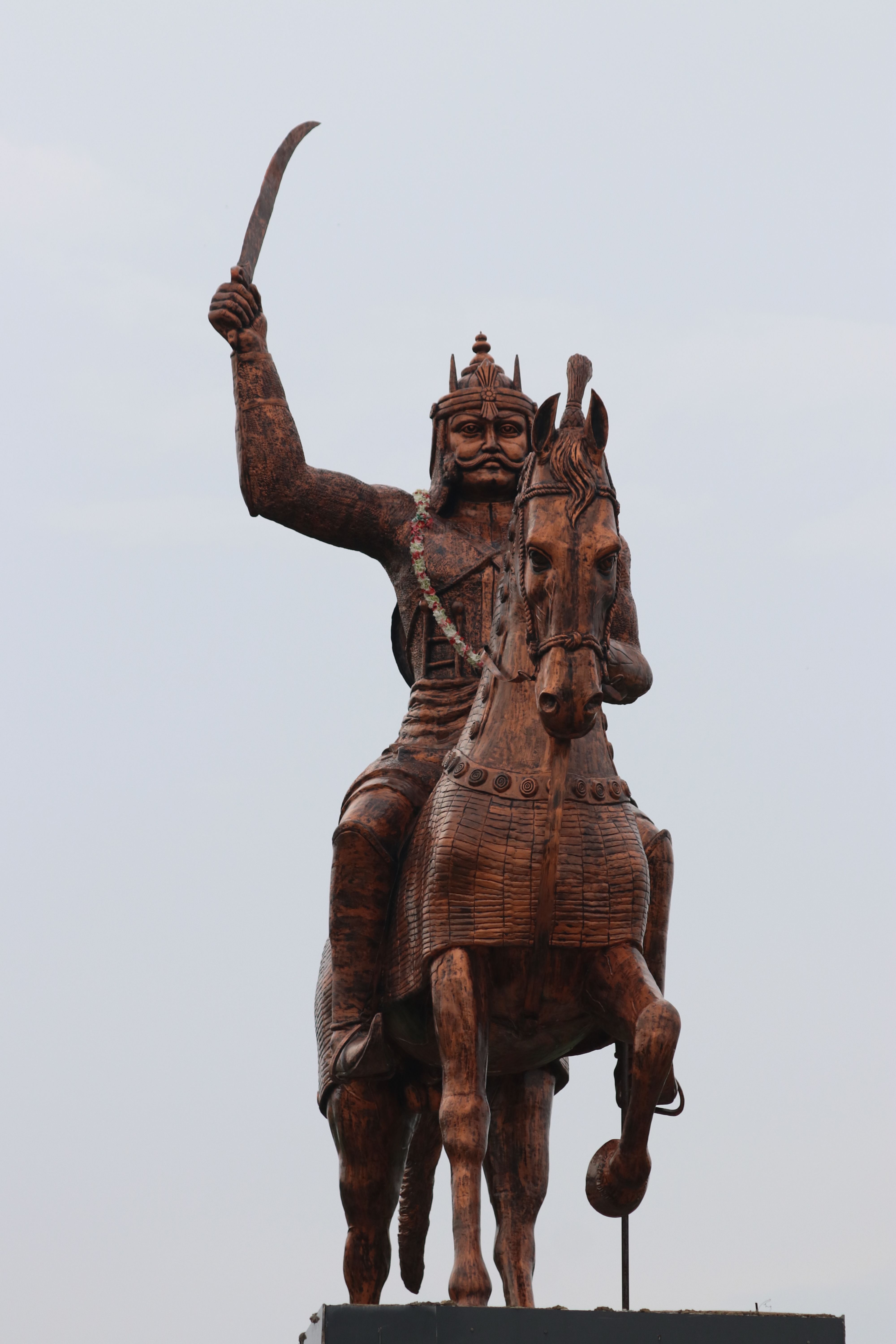 A majestic statue of a warrior on horseback with an uplifted sword against a clear sky.