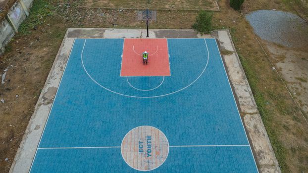 Overhead shot of a vibrant basketball court with a solitary player in Abuja, Nigeria.