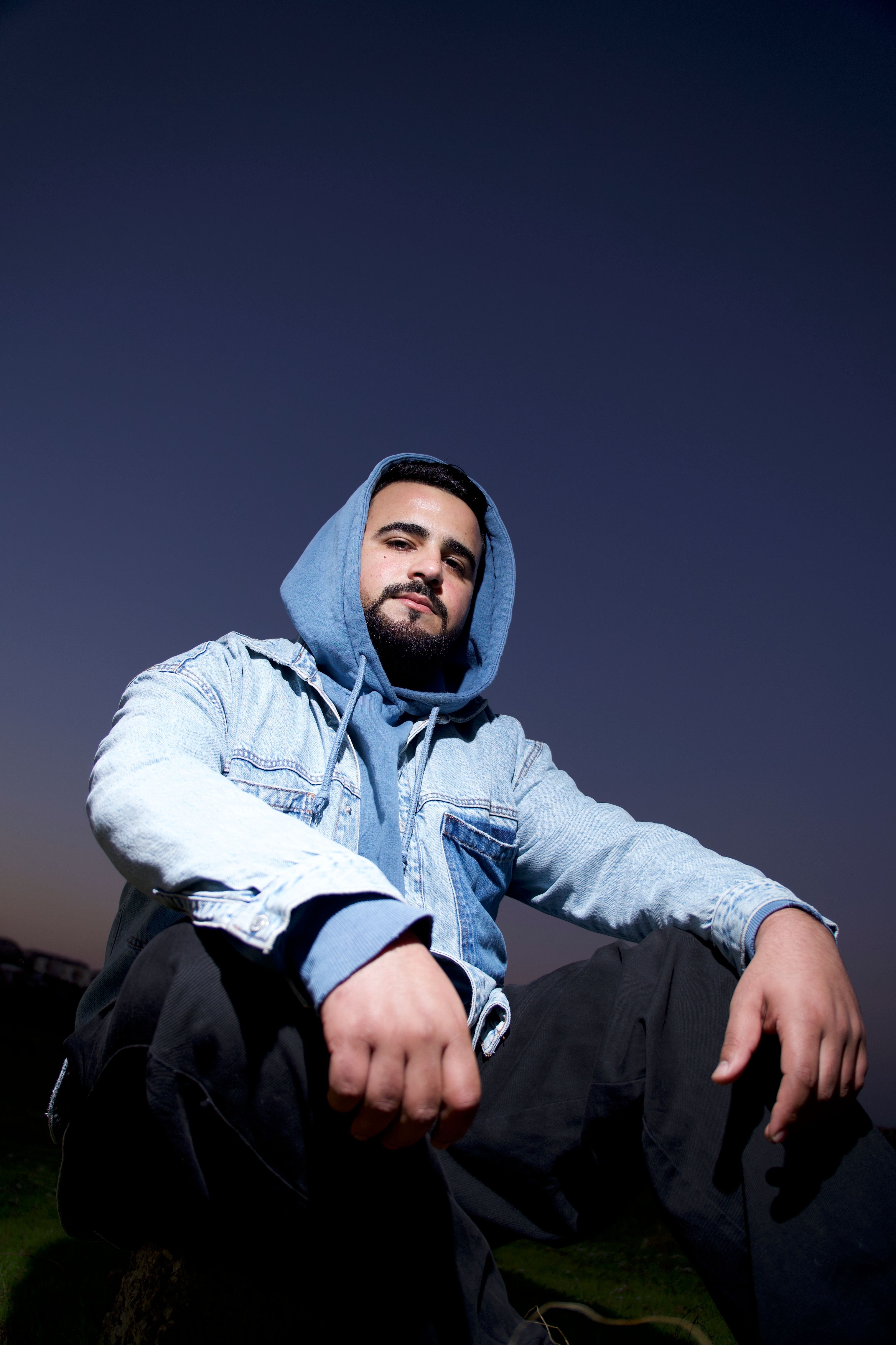 Portrait of a confident young man in casual denim at twilight, expressing urban style.