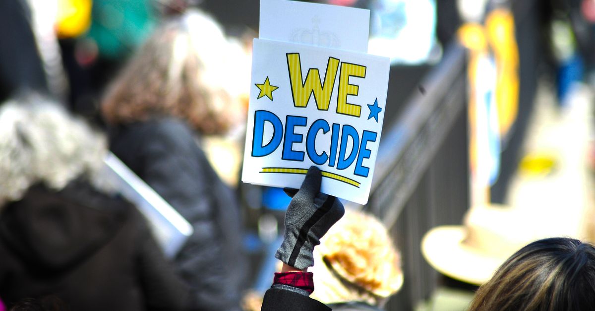 Vibrant protest scene in Baltimore with a sign "We Decide" showcasing civic engagement.
