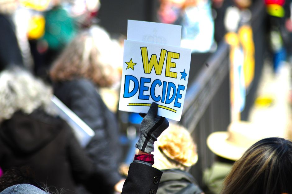 Vibrant protest scene in Baltimore with a sign 'We Decide' showcasing civic engagement.