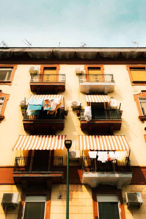 Free Colorful building facade with balconies and striped awnings in Naples, Italy. Stock Photo