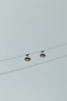 Two cable cars suspended in the sky on a clear day, showcasing transportation technology